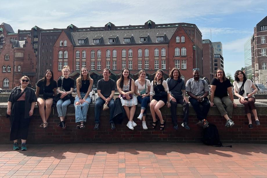 Students sitting in a line on a wall in Germany